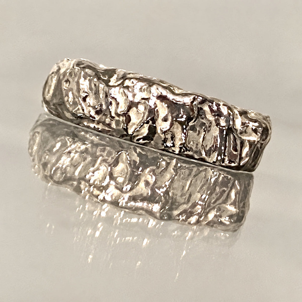 Dettaglio dell’Anello Geo in argento 925: incisioni, rilievi e superfici irregolari evocano falde e formazioni granitiche. Gioiello scultura a cera persa, Made in Italy.
